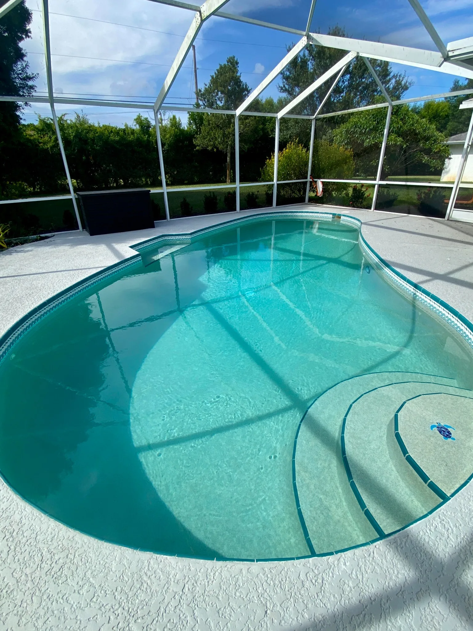 Screen-enclosed residential swimming pool with clear blue water in Port St. Lucie